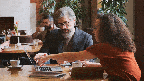 Real estate agent meeting with a client and gesturing at his laptop screen